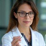 Retrato de Dra. Elena Sánchez, Consultora Científica para Colmena Visual, examinando una muestra con lupa.